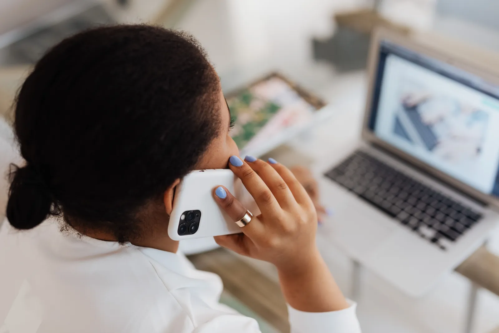 Kvinne snakker i telefon mens hun sitter foran en laptop