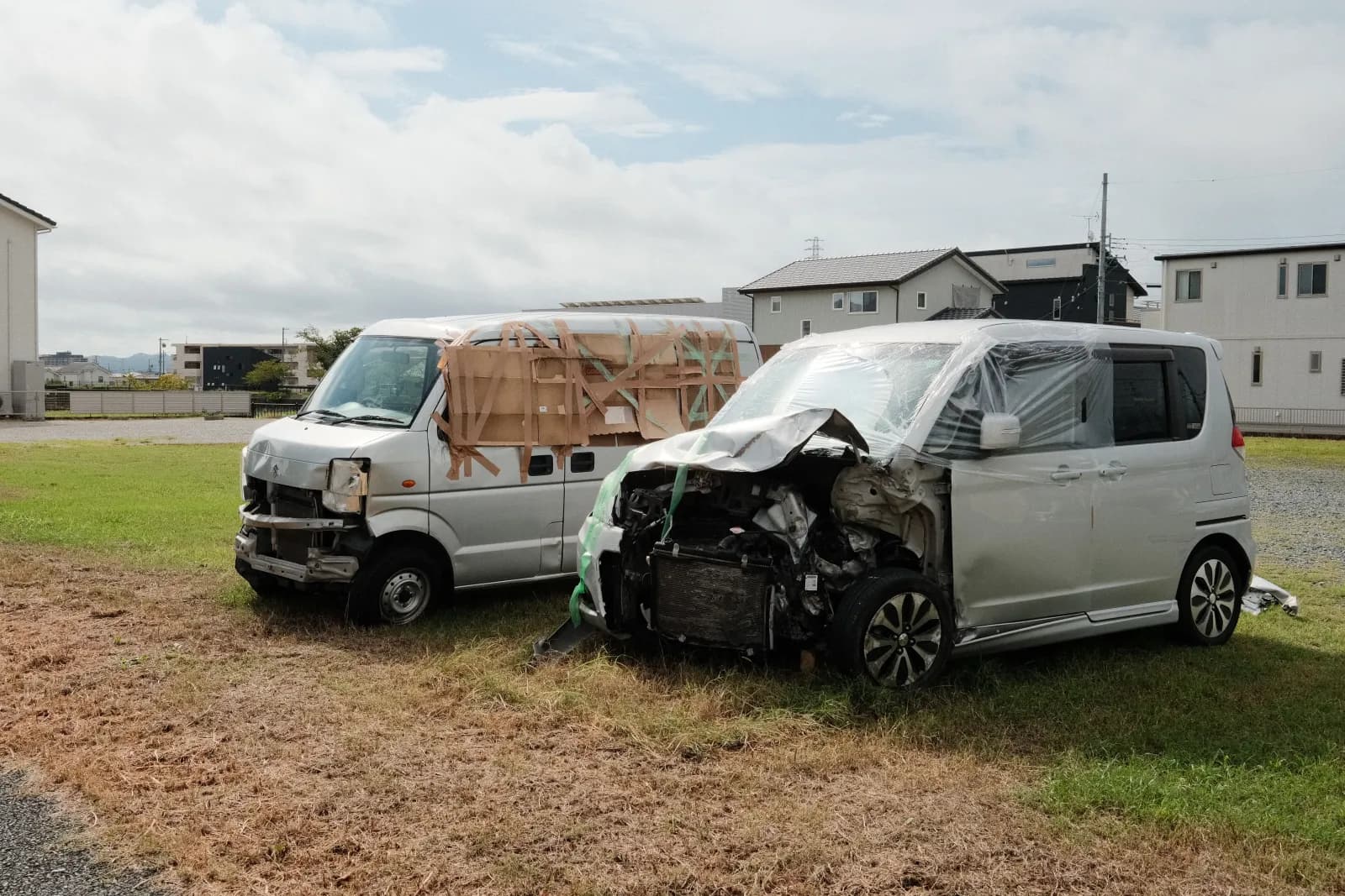 To skadde biler med sammentrykt front parkert på en gressplen